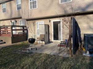 a backyard with a grill and chairs next to a house at Beautiful 3 BR Townhome - Recently Updated! in Bloomington