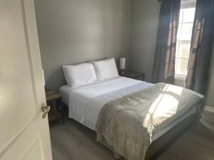 a bedroom with a bed with white sheets and a window at Beautiful 3 BR Townhome - Recently Updated! in Bloomington