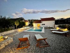 un patio trasero con 2 sillas y una piscina en Vacation House Lavanda NEW! Heated pool, en Zadvarje