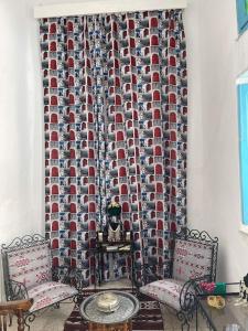 Habitación con 2 sillas, mesa y cortina en Dar Lella Hasna en Sfax