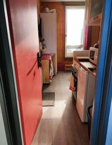 uma pequena cozinha com um frigorífico e uma janela em Le petit Nid Rouge em Ustou