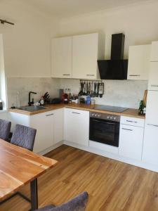 a kitchen with white cabinets and a wooden table at Appartement Herzer in Gabersdorf