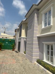a white house with a brick driveway at Ashers Villa in Abuja