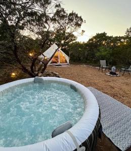 a hot tub with a tent in the background at The Juniper Ranch and Retreat in Canyon Lake