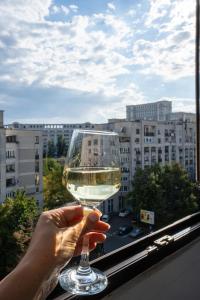 a person holding a glass of wine in a window at Quiet Marble Apt with Free Parking Spot Old Town in Bucharest