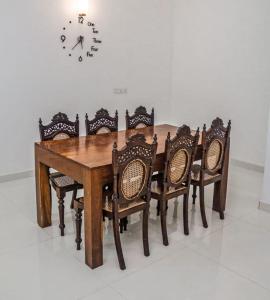 une table en bois avec des chaises et une horloge sur le mur dans l'établissement Villa Double T Residence, à Ambalangoda