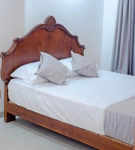 - un lit en bois avec des draps et des oreillers blancs dans l'établissement Villa Double T Residence, à Ambalangoda