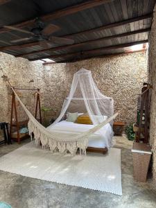 a hammock bed in a room with a stone wall at Cenotefront House 20 min from Chichen Casa Yaxunah 