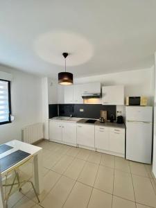 a kitchen with white cabinets and a table in it at Le Cocon des Thermes Amneville Metz Luxembourg in Amnéville