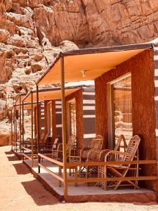 un grupo de sillas sentadas en el porche de una casa en Rum Roza luxury camp, en Wadi Rum