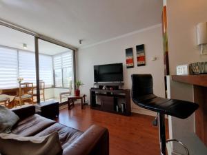 ein Wohnzimmer mit einem Sofa und einem TV in der Unterkunft Santiago Moneda Suites in Santiago