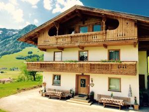 a house in the mountains with benches in front of it at Steindlhof in Walchsee in Walchsee