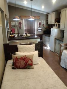 a kitchen with white cabinets and a table with pillows at Rubyred Cottage in Bloemfontein