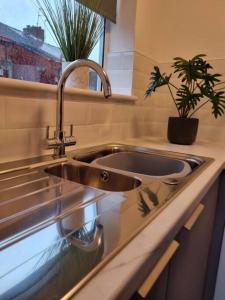 a kitchen sink with a potted plant on a counter at Home from Home Liverpool - Entire Home in Liverpool