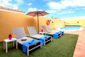 une terrasse avec des chaises et un parasol ainsi qu'une piscine dans l'établissement Villa Playa (Los Cristianos), à Los Cristianos