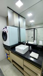 a bathroom with a sink and a washing machine at Loft Família c/ 2 Quartos e Lava e Seca no Vertigo in Campo Grande