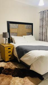 a bedroom with a large bed and a night stand with a lamp at The Blyde Crystal Lagoon By Damo in Pretoria