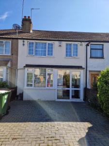 a house with glass doors and a brick driveway at Lovely 4 bed house with patio & bbq in Slades Green