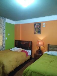 a bedroom with two beds and a lamp on a table at hostal andina joya in Puno