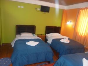 Habitación de hotel con 2 camas con colchas azules en hostal andina joya, en Puno