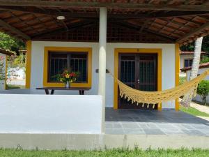 une maison avec un hamac en face de celle-ci dans l'établissement Bitingui Praia Hotel, à Japaratinga