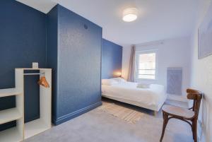 1 dormitorio con cama, silla y pared azul en Le repère de Poincaré, en Nancy