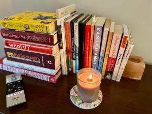 a candle sitting on a table next to a stack of books at Modern, Gr Floor 1 bed, bathroom, garden & private entry. in Cambridge