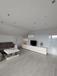 a white living room with a couch and a tv at Wolke7 in Frittlingen
