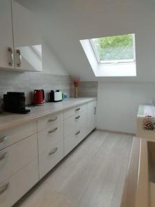 a kitchen with white cabinets and a skylight at Wolke7 in Frittlingen