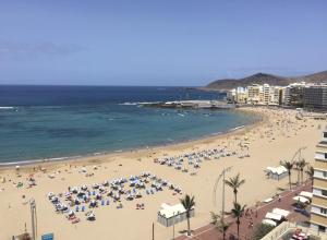 a beach with a lot of people and the ocean at Las Canteras Beach in Las Palmas de Gran Canaria