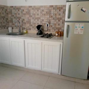 a kitchen with white cabinets and a refrigerator at Magnifique appartement djerbien in El Guecheïne