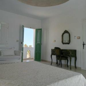 a bedroom with a bed and a table and a mirror at Magnifique appartement djerbien in El Guecheïne