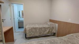 a bedroom with a bed and a sink and a mirror at Departamento en Bombhinas in Bombinhas +11 photos