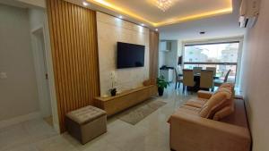 a living room with a couch and a television on a wall at Departamento en Bombhinas in Bombinhas