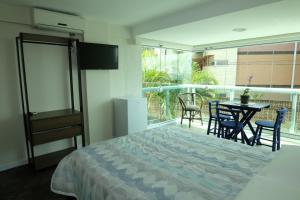 a bedroom with a bed and a balcony with a table and chairs at Hostel Toca da Moréia Bombinhas in Bombinhas