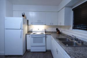une cuisine blanche avec un réfrigérateur blanc et un évier dans l'établissement 410 E 45th Unit 1, à Anchorage