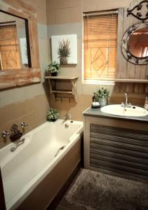 a bathroom with a tub and a sink at Rubyred Cottage in Bloemfontein