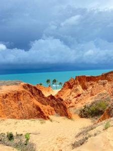 a beach with two palm trees and the ocean at Cantinho Casa Grande in Beberibe