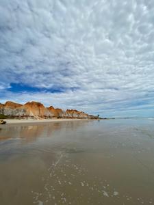 a beach with a cloudy sky and the water at Cantinho Casa Grande in Beberibe