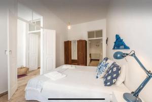 a white bedroom with a bed and a blue lamp at Traditional townhouse with private patio and pool in Portimão