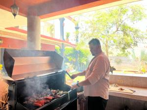 Ein Mann kocht Würstchen auf einem Grill in der Unterkunft Casa Punta Perula VILLAS in Pérula