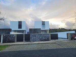 ein weißes Haus mit einer Steinwand in der Unterkunft Casa das Azorinas in Fenais da Luz