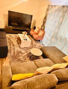 a living room with a couch and a flat screen tv at Courtyard tranquil lodge in London