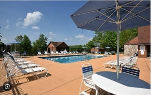 a pool with a bunch of chairs and an umbrella at Townhouse in Seven Springs 3bed 2bath sleeps 8 aircon wifi in Champion