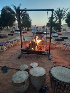 een vuurplaats met krukken ervoor bij desert camp in Adrouine