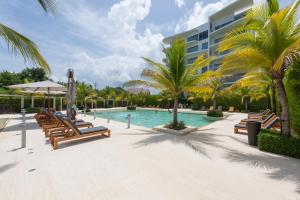 a resort swimming pool with benches and palm trees at Lujoso Apartamento Con Salida Directa A La Playa Edificio Morros Eco in Cartagena de Indias