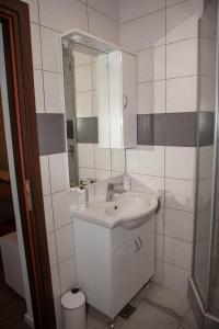 La salle de bains blanche est pourvue d'un lavabo et d'un miroir. dans l'établissement July Holiday House, à Dugo Selo
