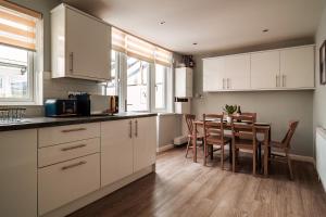 a kitchen with white cabinets and a table with chairs at Luxury Affordable Business Stay with Hot Tub and Pool Table in Enfield Lock