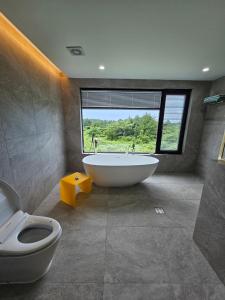 bagno con vasca, servizi igienici e finestra di Almare Woljeong a Jeju