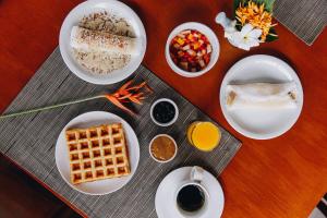 a table with plates of food and waffles and drinks at Pousada Alto da Pipa in Pipa